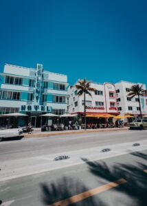 Farbenfrohe Szene mit historischem Ocean Drive in Miami Beach mit palmengesäumter Straße und ikonischen Art-Deco-Hotels.