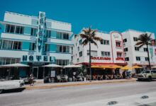 Farbenfrohe Szene mit historischem Ocean Drive in Miami Beach mit palmengesäumter Straße und ikonischen Art-Deco-Hotels.