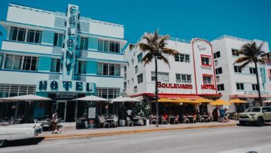 Farbenfrohe Szene mit historischem Ocean Drive in Miami Beach mit palmengesäumter Straße und ikonischen Art-Deco-Hotels.