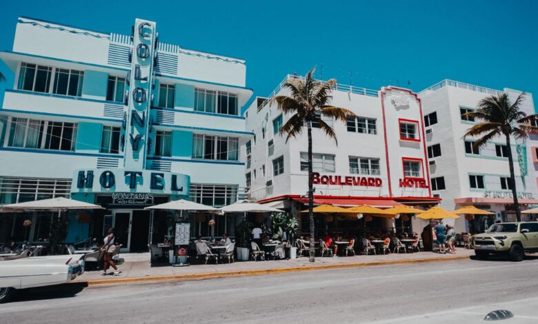 Farbenfrohe Szene mit historischem Ocean Drive in Miami Beach mit palmengesäumter Straße und ikonischen Art-Deco-Hotels.